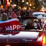 Children riding in the back of a vintage car huddle under the cover of a banner with the phrase, Happy Homecoming, as they wave to thousands of spectators lining State Street during the University of Wisconsin-Madison's Homecoming Parade on Oct. 16, 2015. The annual parade is one of many Homecoming week activities sponsored by the Wisconsin Alumni Association (WAA). (Photo by Jeff Miller/UW-Madison)
